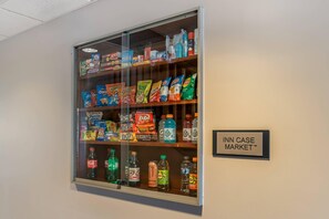 Ett skyltfönster med texten ”INN CASE MARKET” som visar olika sorters snacks och drycker.
