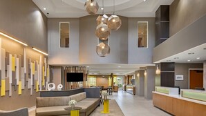 Eine moderne Hotelhalle mit Rezeption, Sitzgelegenheiten und einem großen Fenster.