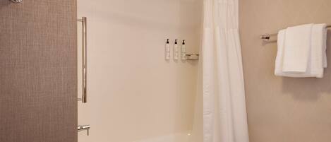 Un baño moderno con ducha de vidrio, una bañera y un perchero con toallas.