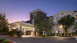 Ein Hotel mit Backsteinfassade, überdachter Eingangspartei und Parkplatz.