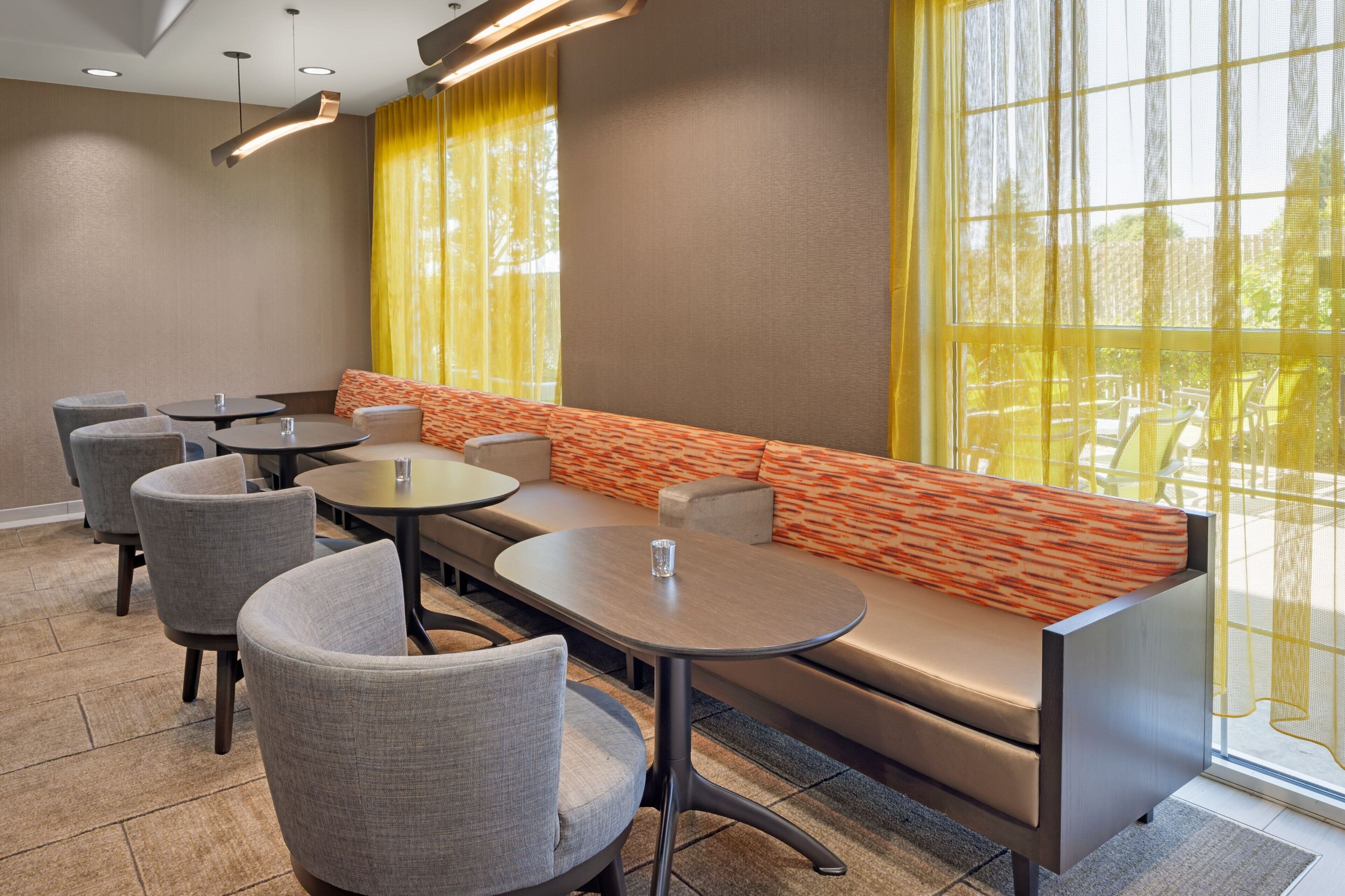 A modern dining area with a long bench, round tables, and chairs.