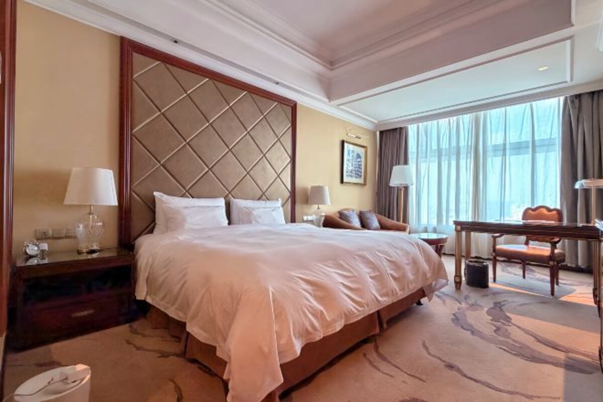 Ein Hotelzimmer mit einem großen Bett, Nachttischen, einem Schreibtisch und einem Sessel.