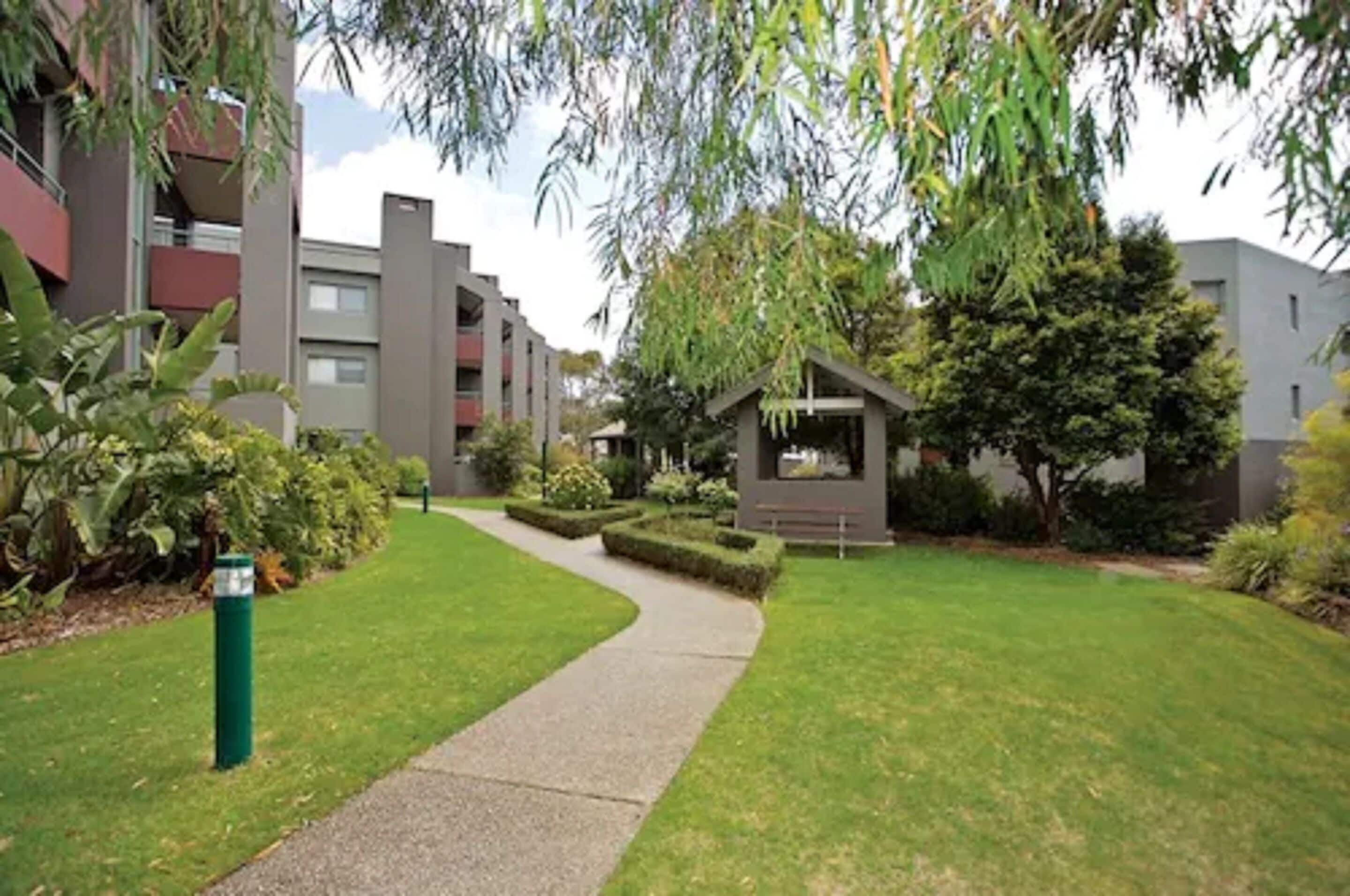 Un edificio residencial con un sendero que lleva a un pequeño jardín.