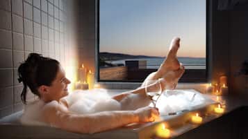 Relax in a serene space with a bathtub, candles, and a view of the water.
