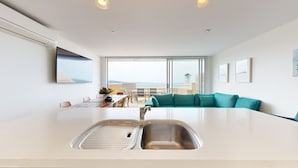Cozinha moderna com uma ilha grande, área de jantar com vista e um sofá verde-água.
