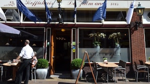 A hotel with a brick facade, outdoor seating, and flags. - Fletcher Hotel - Restaurant De Zalm (Brielle)