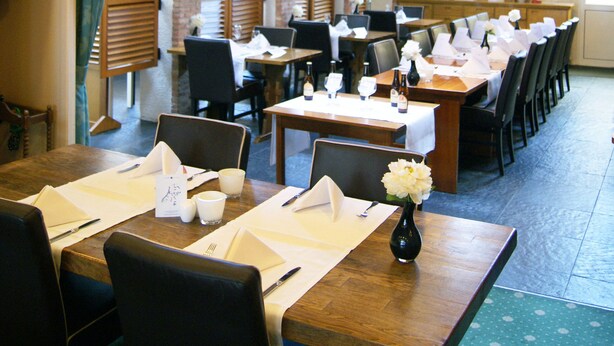 A restaurant with brick walls, wooden tables, and black chairs. - Fletcher Hotel - Restaurant De Zalm (Brielle)