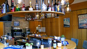 A bar area with a variety of liquor bottles, a coffee machine, and seating. - Fletcher Hotel - Restaurant De Zalm (Brielle)