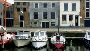 A canal with boats docked and buildings with distinct architectural styles in the background. - Fletcher Hotel - Restaurant De Zalm (Brielle)