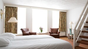 A hotel room with a large bed, two armchairs, a small table with a vase, and a staircase. - Fletcher Hotel - Restaurant De Zalm (Brielle)