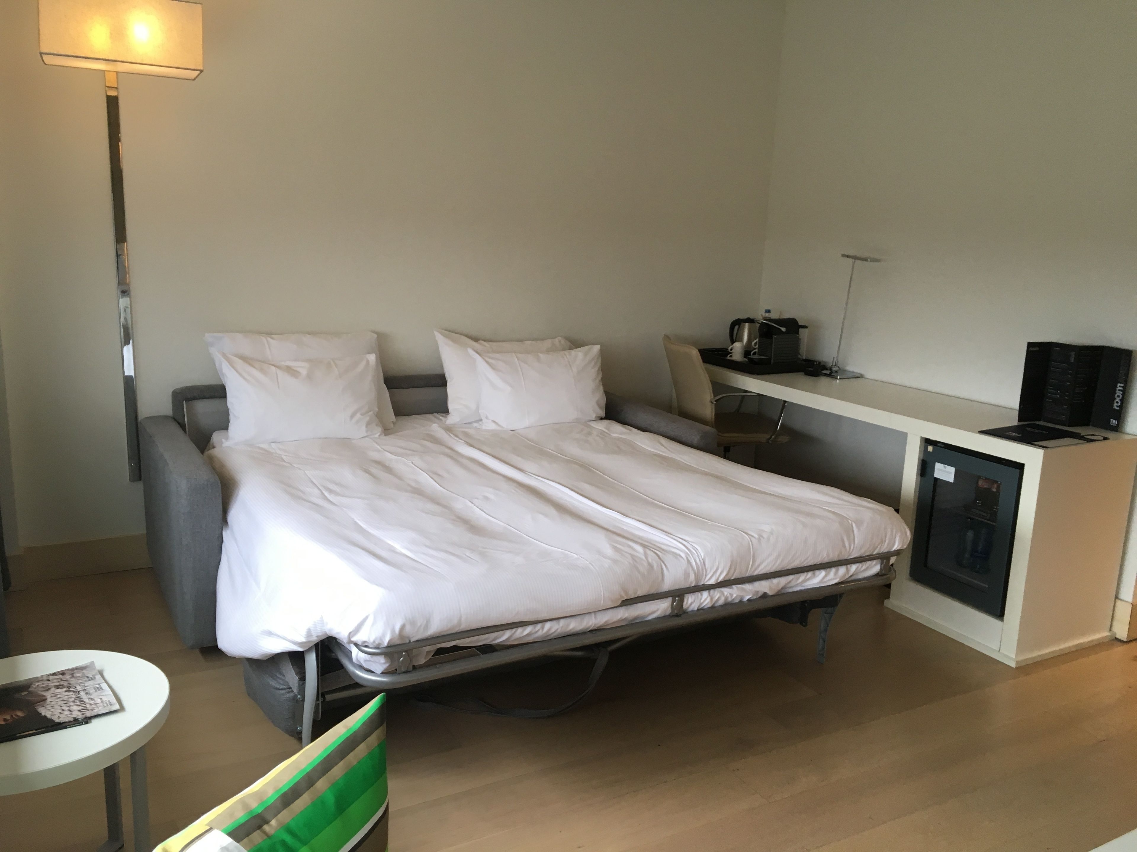 Una habitación de hotel compacta con una cama individual, un escritorio y una pequeña cocina.