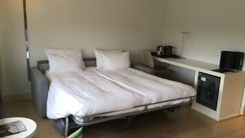 Una habitación de hotel compacta con una cama individual, un escritorio y una pequeña cocina.