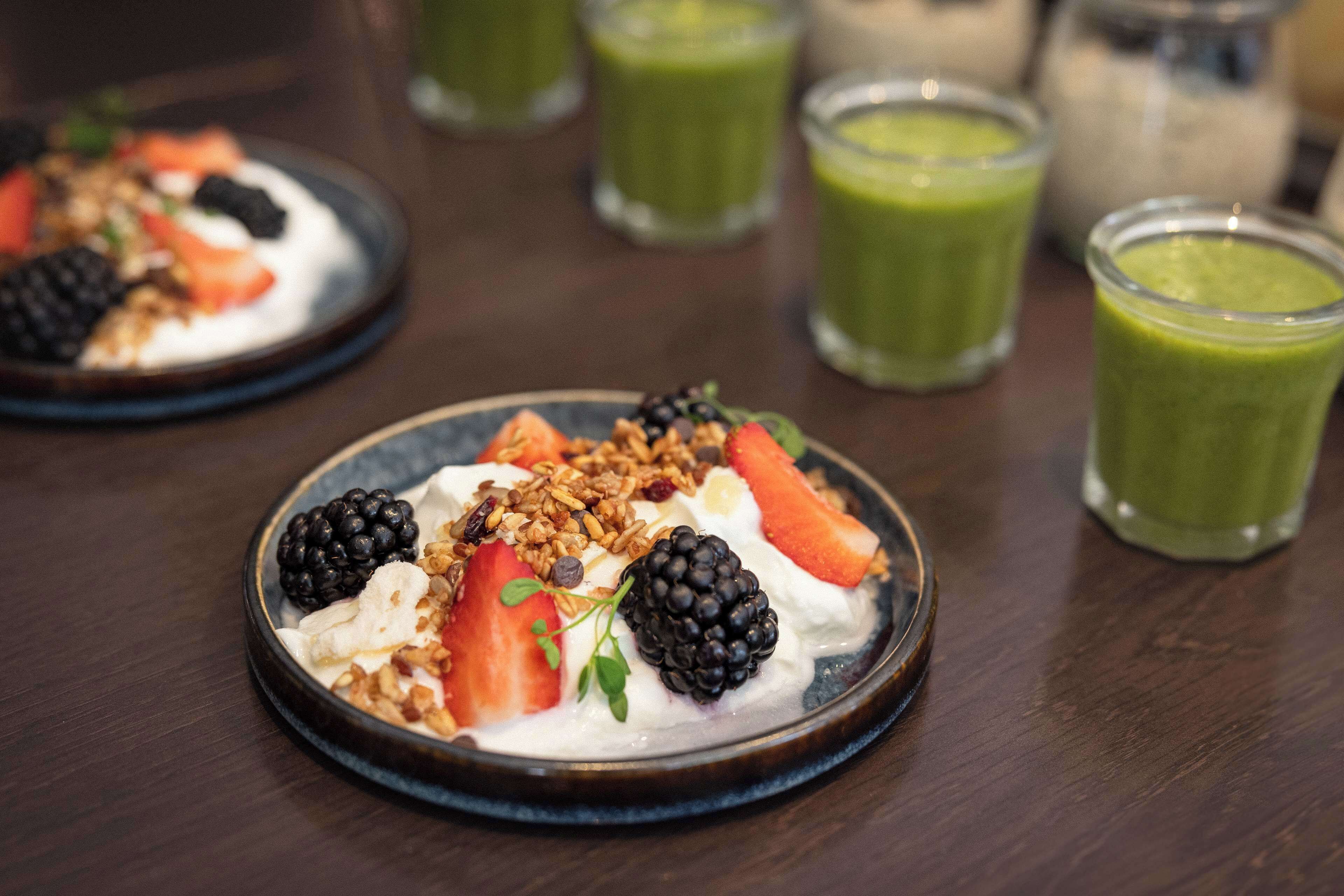 A dessert plate with strawberries, blackberries, granola, and whipped cream.