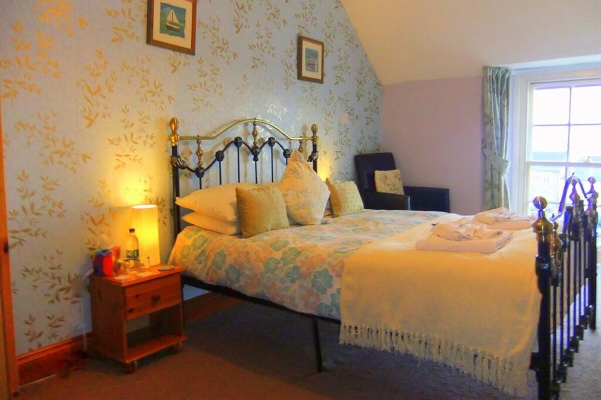 A bedroom with a bed, nightstand, and a window with curtains.