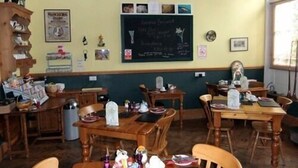 Un restaurante acogedor con mobiliario de madera y una pizarra con la carta.
