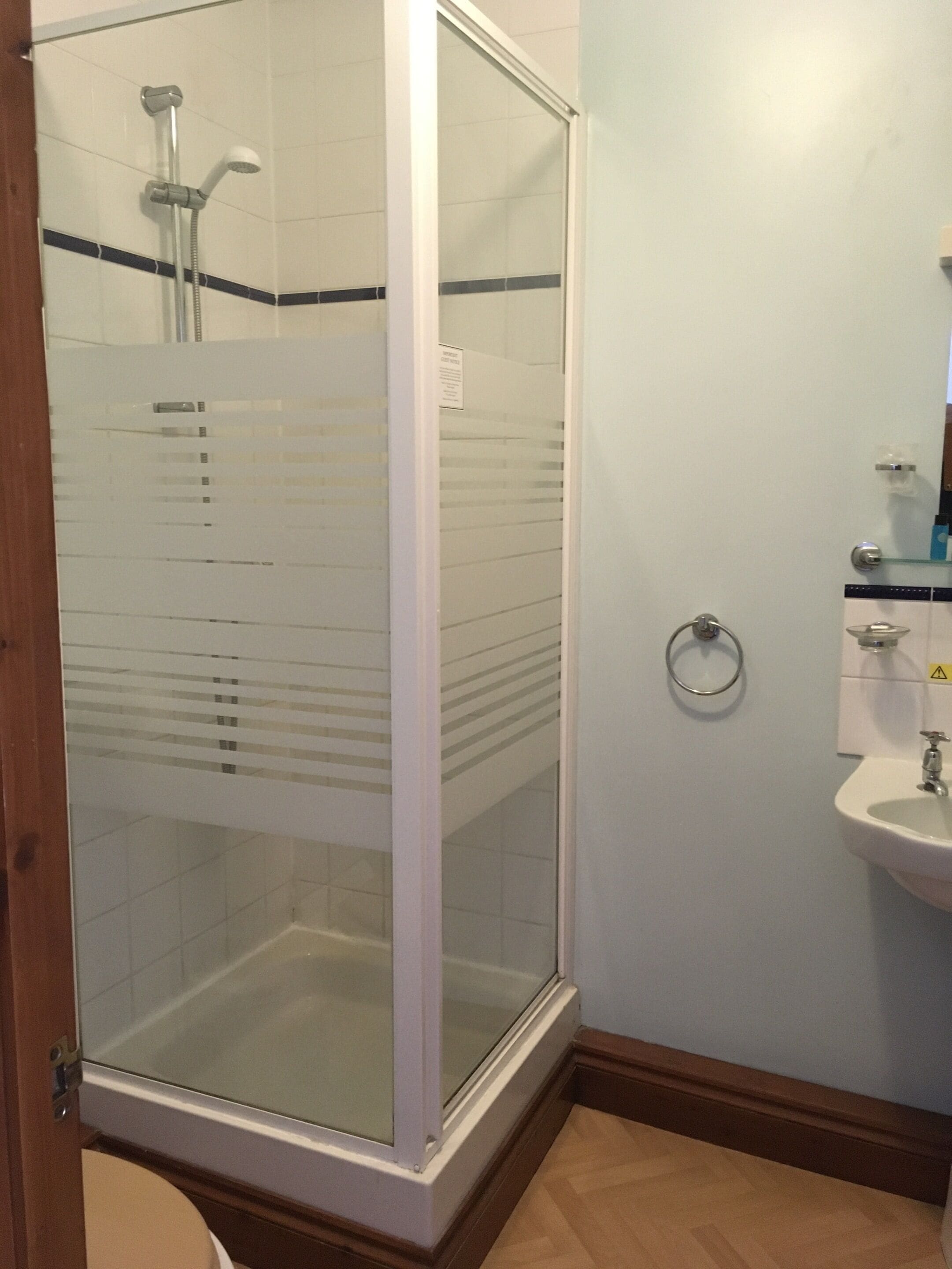 Un baño con ducha de vidrio, lavamanos e inodoro.