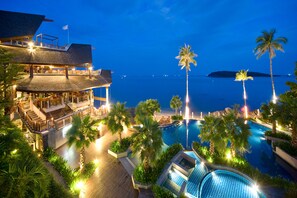 Un resort con una gran piscina, palmeras y vistas al océano.