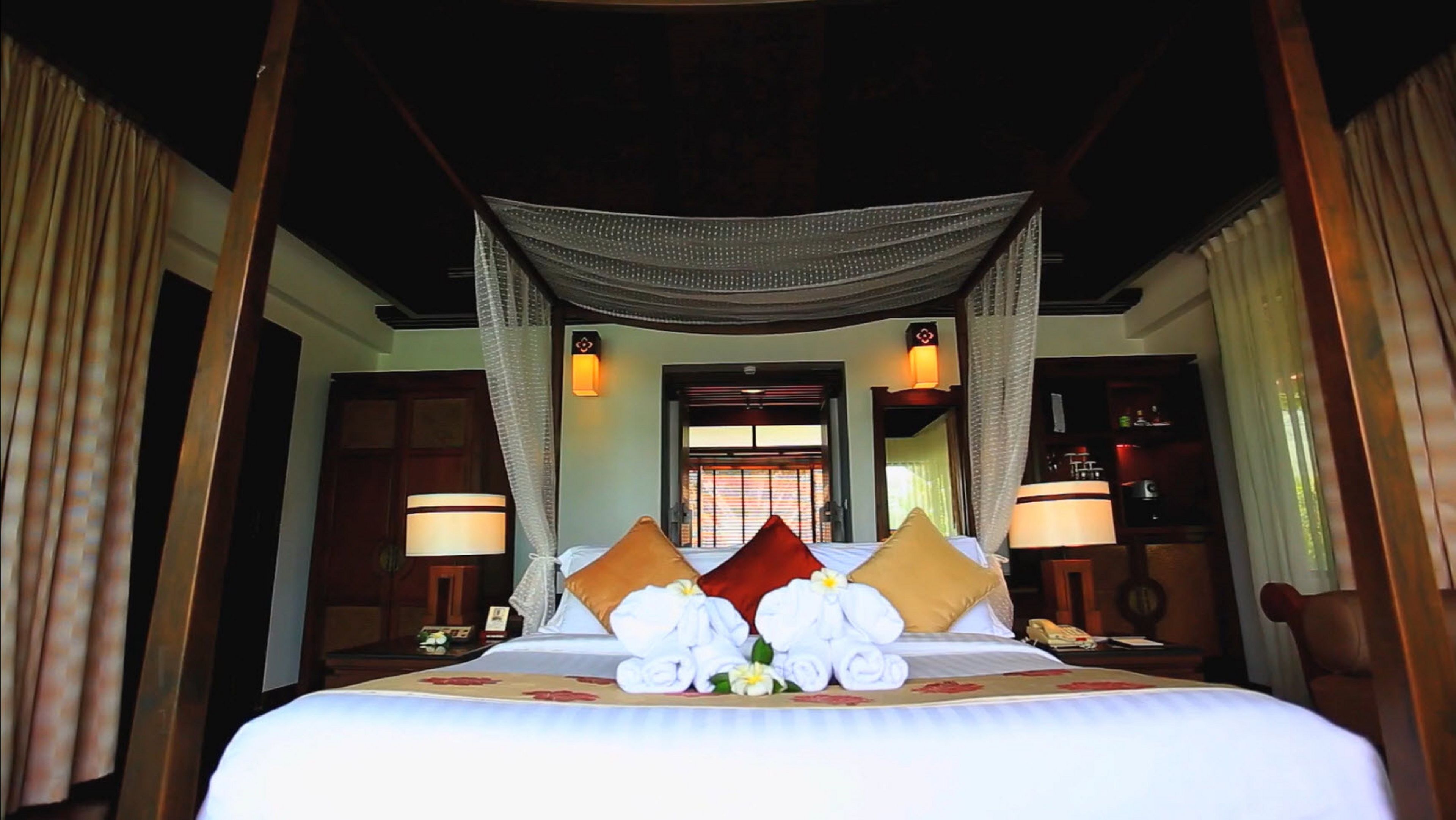 A hotel room with a large bed, a canopy, and a view of the outside.