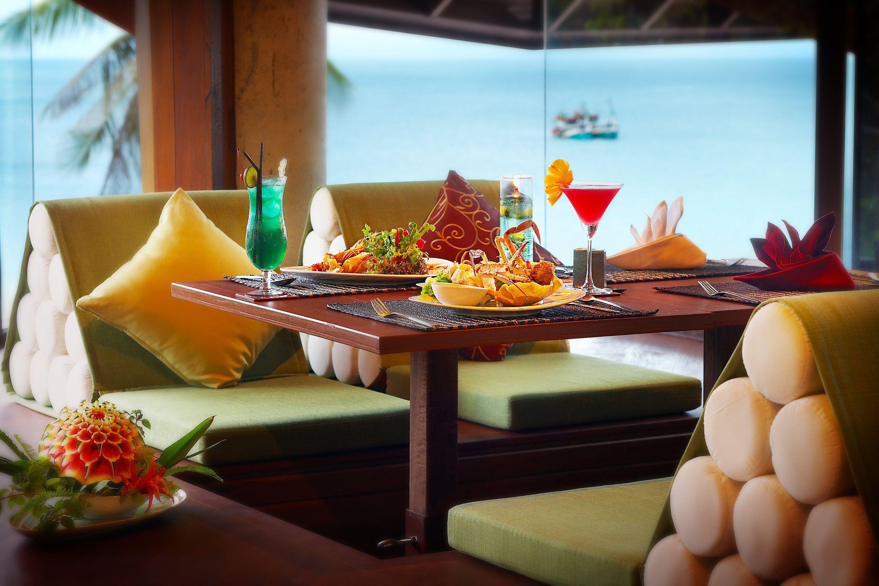 A dining table set with a variety of dishes, drinks, and a view of the ocean.