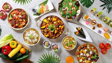 A variety of dishes and fresh vegetables arranged on a wooden table.