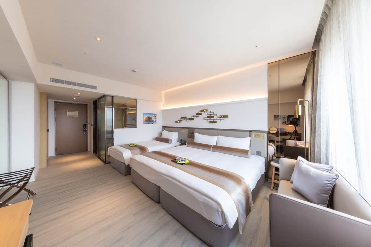 Een moderne hotelkamer met een groot bed, twee nachtkastjes, een bank en een spiegel.