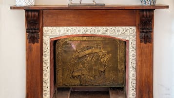 A fireplace with a framed painting above it, a decorative horse statue, and two patterned vases on either side.