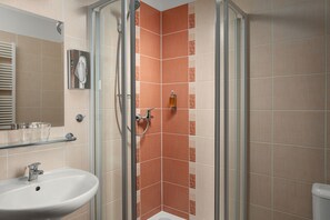 Un baño con ducha de vidrio, lavamanos y espejo.