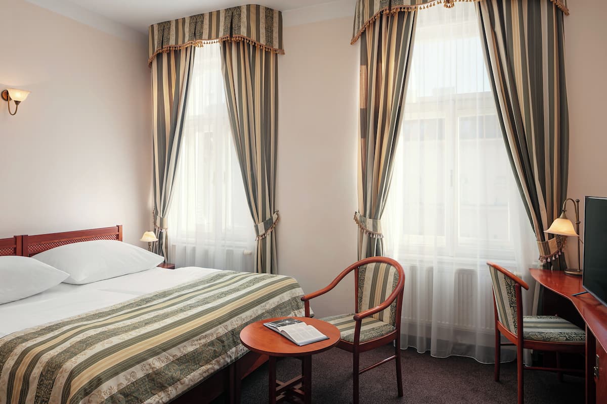 Een hotelkamer met een bed, een stoel, een klein tafeltje en een televisie.