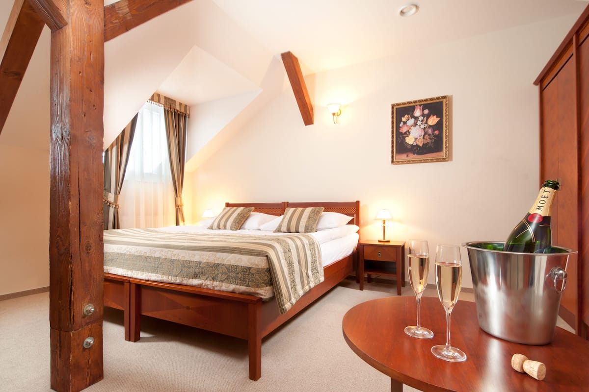 Een slaapkamer met een houten bed, een nachtkastje met twee champagneglazen, en een champagnefles in een metalen emmer.