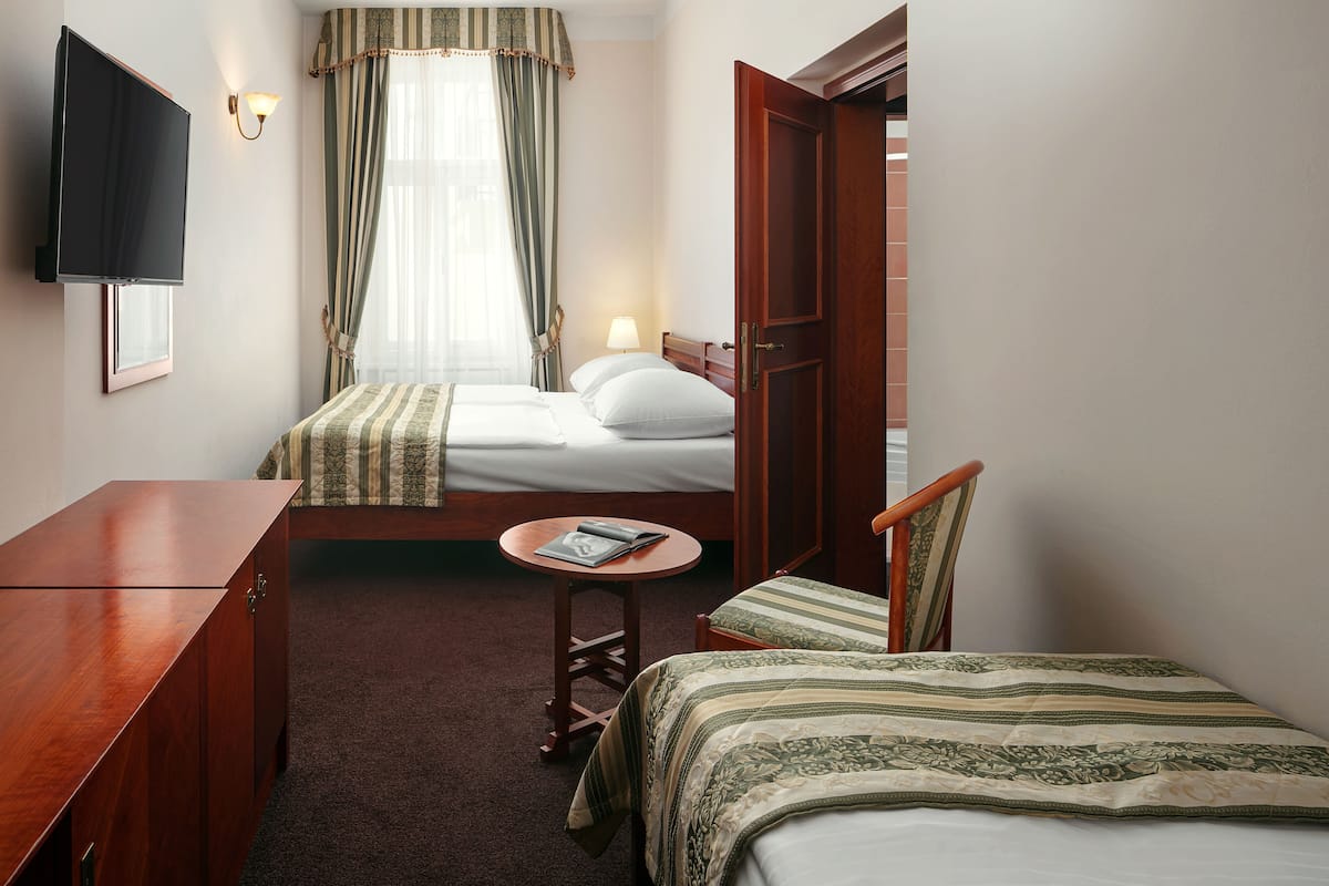 Een hotelkamer met een bed, een bureau, een stoel, een tafeltje en een televisie die aan de muur hangt.