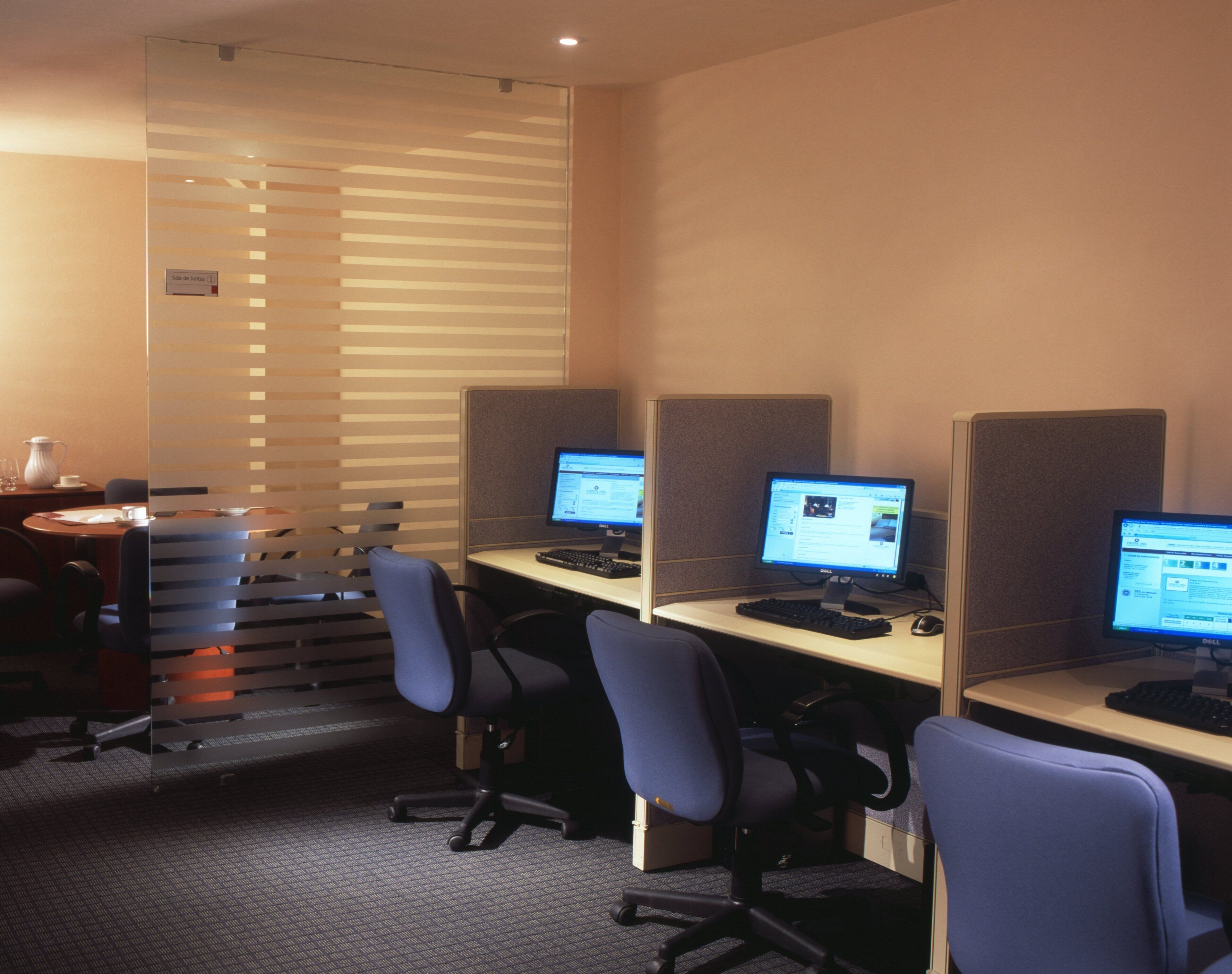 A modern office space with cubicles, each equipped with a desktop computer, keyboard, and mouse.