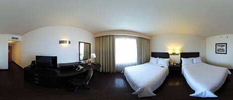 Habitación de hotel con una cama grande, un escritorio con silla, televisor y ventana con cortinas.