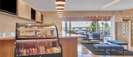 A modern kitchen with a glass display case containing food items, a coffee machine, and a beverage cooler.