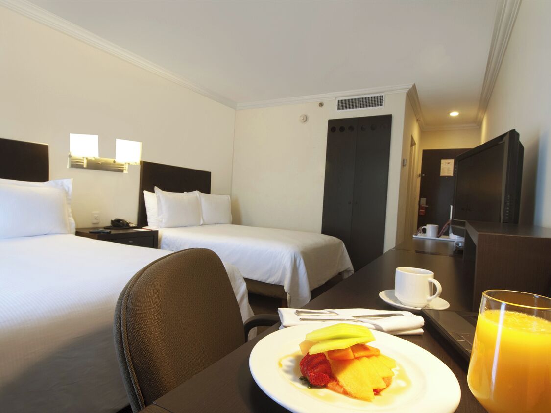 Une chambre d’hôtel avec deux lits, une table à manger avec le petit-déjeuner, une télévision et un four à micro-ondes.