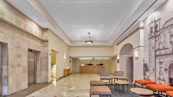 En rummelig lobby med reception, siddeområde og et vægmaleri.