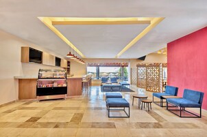 Un hall de hotel con mostrador de panadería, zona de estar y vistas al exterior.