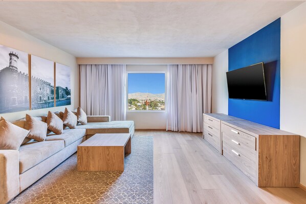 Una sala de estar moderna con un sofá, una mesa de centro y un televisor montado en una pared azul.