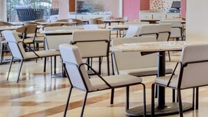 A modern dining area with multiple tables and chairs, featuring a central island with a counter.