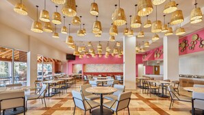 A spacious restaurant with multiple dining tables and chairs, a checkered floor, and numerous hanging wicker pendant lights.