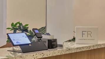 Un mostrador de recepción con una tableta, un teléfono y un cartel de FIESTA REWARDS.