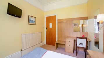 A hotel room with a bed, a desk, a wardrobe, a mirror, a TV, and a radiator.
