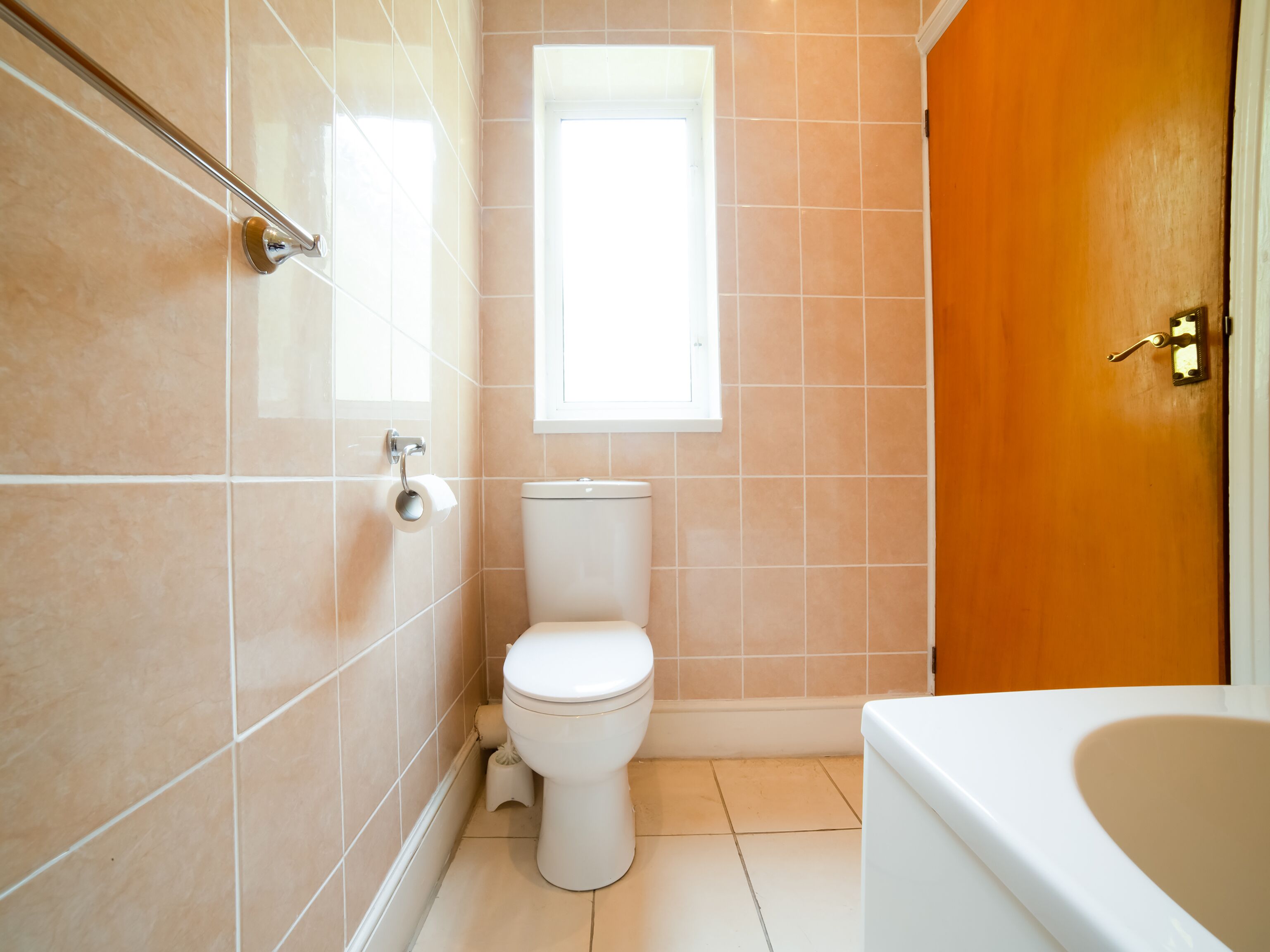 A bathroom with a toilet, a window, and a bathtub.