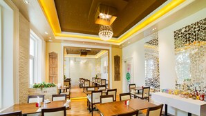 Um restaurante espaçoso com mesas e cadeiras de madeira, painéis decorativos na parede e um candelabro.