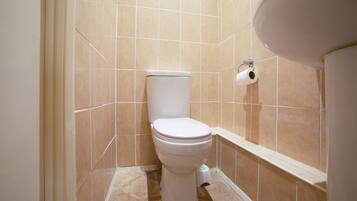 Un baño pequeño con inodoro, dispensador de papel higiénico y lavamanos.
