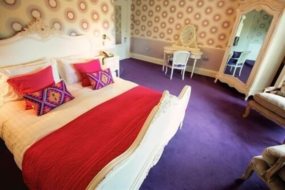 A bedroom with a bed, a desk, and a chair.