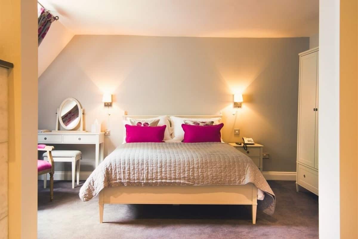 A bedroom with a bed, bedside lamps, a desk, and a wardrobe.