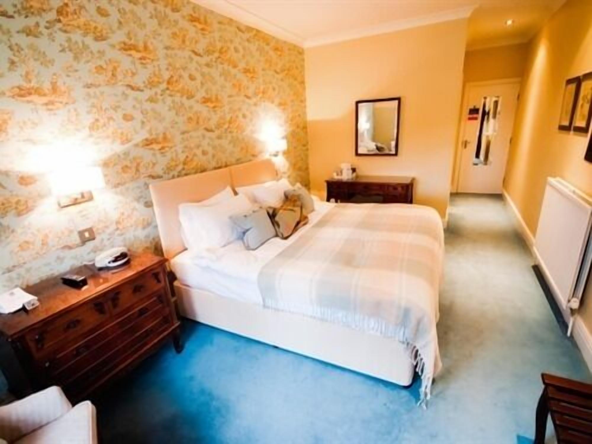 Une chambre à coucher avec un lit, des tables de chevet, une commode et un miroir au mur.