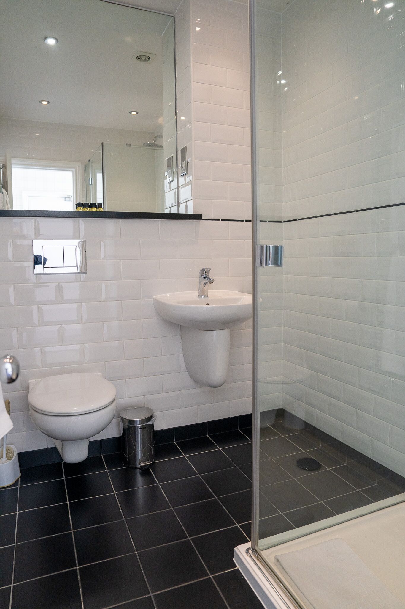 Ein modernes Badezimmer mit Toilette, Waschbecken und Duschkabine aus Glas.