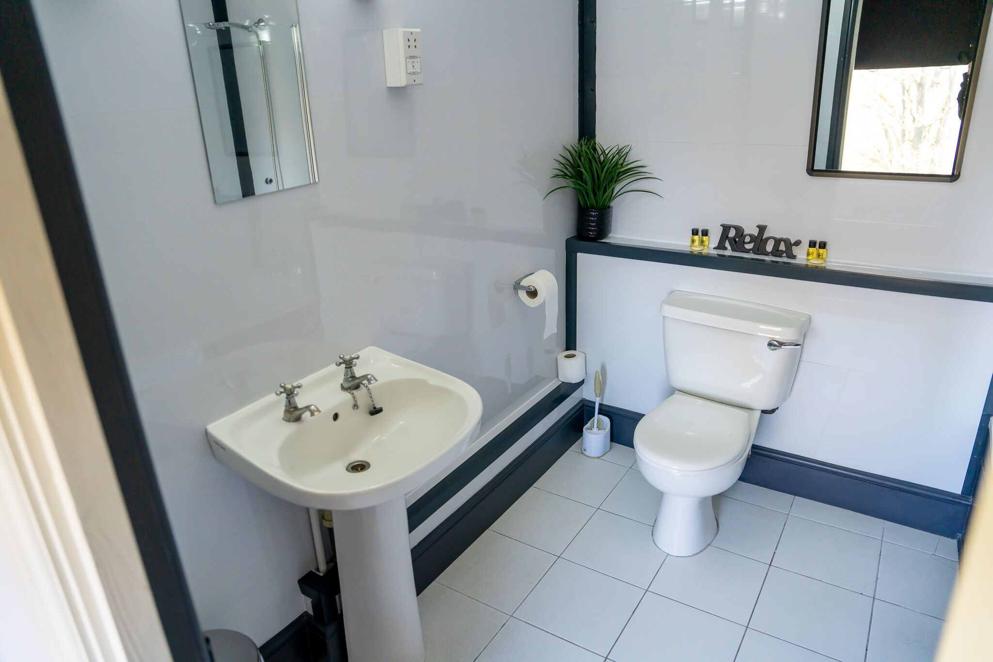 Un baño con lavamanos, inodoro y espejo.
