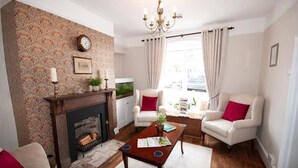 Una sala de estar con chimenea, dos sillones, una mesa de centro y un candelabro.